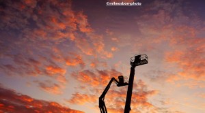 Two cherrypickers set against the sunset in Salford