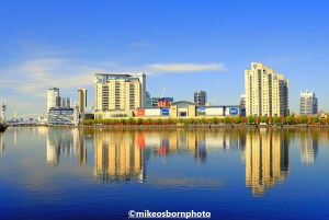 The buildings of Salford Quays reflected in the blue waters of the Manchester Ship Canal