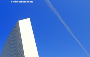 The Imperial War Museum North against a blue sky scratched by an airplane trail