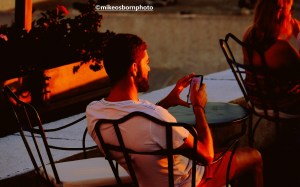 A man views his phone during the sunset in Santorini, Greece