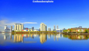 Buildings of Salford Quays reflected in blue waters of the Manchester Ship Canal