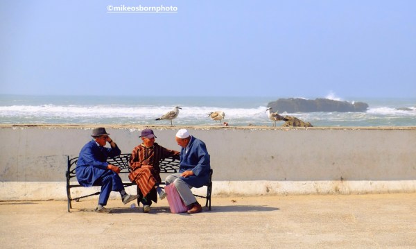 Three elderly Moroccan men meet on a bench in Essaouira