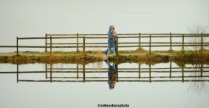 Winter walkers cross a causeway on a foggy day at Entwistle Reservoir, Lancashire