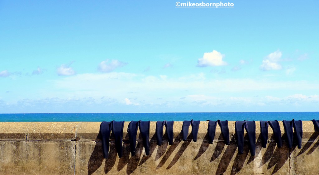 Wet suits drying on a seaside wall in Cromer, Norfolk, UK