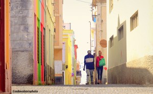 A couple walk along a brightly coloured street in Mindelo, Cape Verde