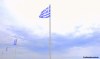 Greek flags flutter in the wind at the port of Tinos island, Greece