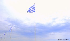 Greek flags flutter in the wind at the port of Tinos island, Greece
