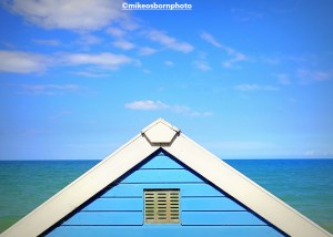 A blue beach hut set against the blue sea and sky in Cromer, Norfolk, UK.