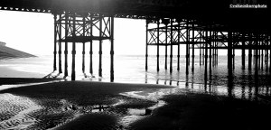 The wet sand and pier struts on Blackpool beach.