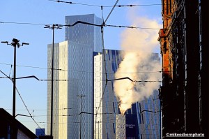 A steam plume in freezing weather among the tall buildings of Manchester.