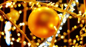 A golden Christmas tree bauble and twinkly lights in the background.