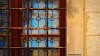 An ornate window covered by a rusty grille in Kotor, Montenegro.
