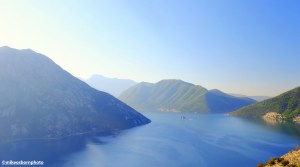 Early morning sunlight bathes the water and surrounding mountains of Boka Bay in Montenegro.