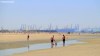 Summer visitors to a Dutch beach with the industrial might of Hoek Van Holland in the background.