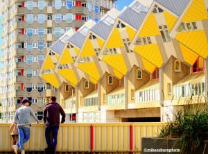 Two visitors look at Rotterdam's iconic yellow cube houses.