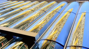 The curved glass of a modern office block in central Rotterdam catches the reflection of another nearby building.