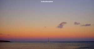 A solo boat moored on the Atlantic Ocean during a peach-coloured sunset over FUerteventura.