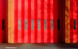 The sun-dappled red shutter doors of a fire station in Manchester city centre.