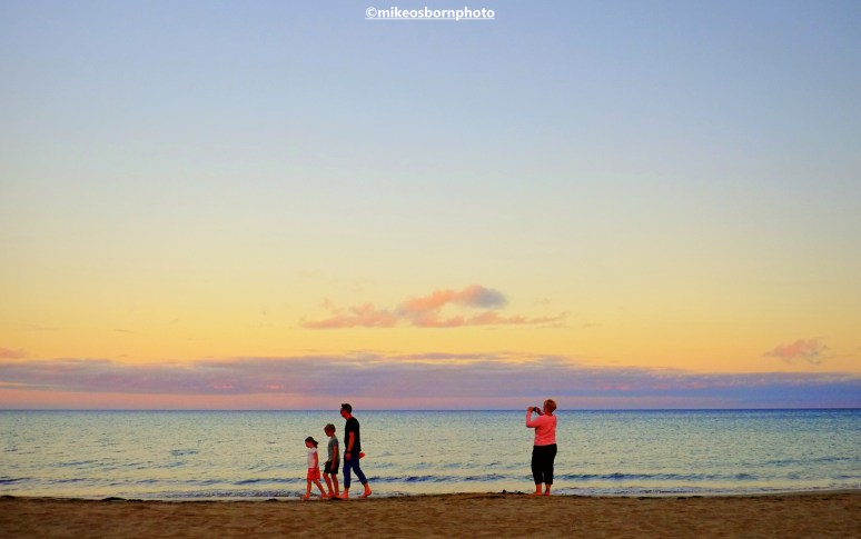 A family of four enjoy a sunset walk on the shores of Costa Calma in Fuerteventura.