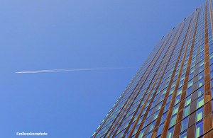 A high rise building of New Jackson, Manchester set against a blue sky scratched by a con trail.