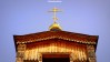 The wooden tower of Karakol's Orthodox cathedral in Kyrgyzstan topped with a gold cross.