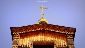 The wooden tower of Karakol's Orthodox cathedral in Kyrgyzstan topped with a gold cross.