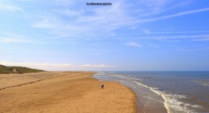A couple walk along the beach of Blackpool's South Shore on a summer's day.