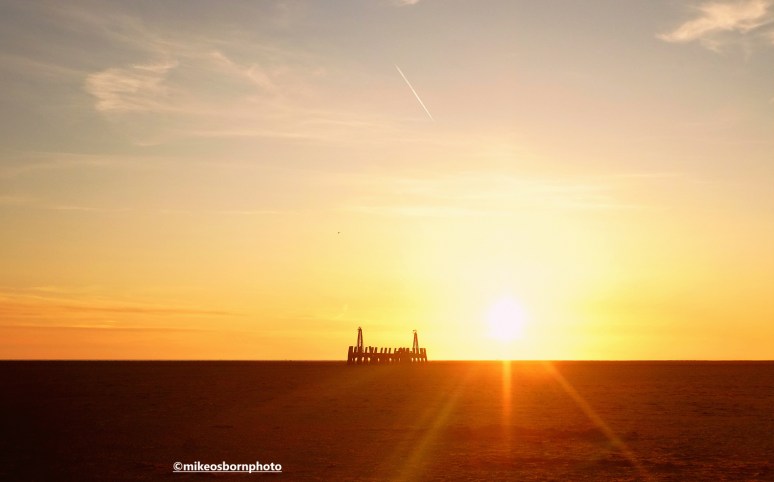 The sinking sun over St Anne's Beach in Lancashire, featuring the pier's old jetty.