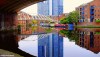 A view of the buildings of Castlefield. Manchester reflected in very still waters of the canal.