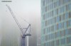 A crane and new high rise buildings of Manchester fading into a cloak of fog.