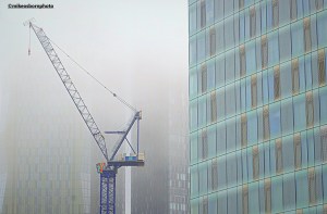 A crane and new high rise buildings of Manchester fading into a cloak of fog.
