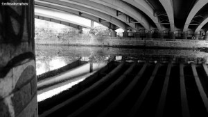 The underside of a bridge over Manchester's River Irwell reflected in the water.